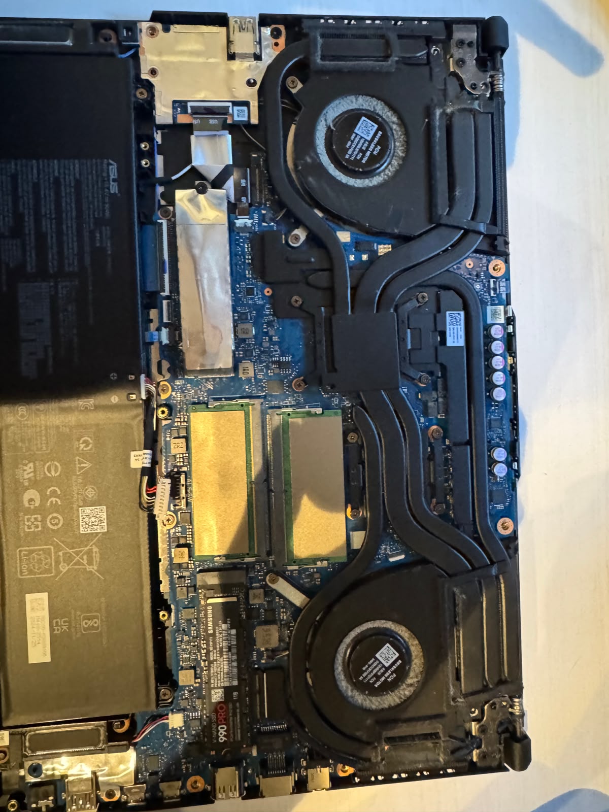 Portátil desmontado mostrando placa, ventiladores, RAM y SSD